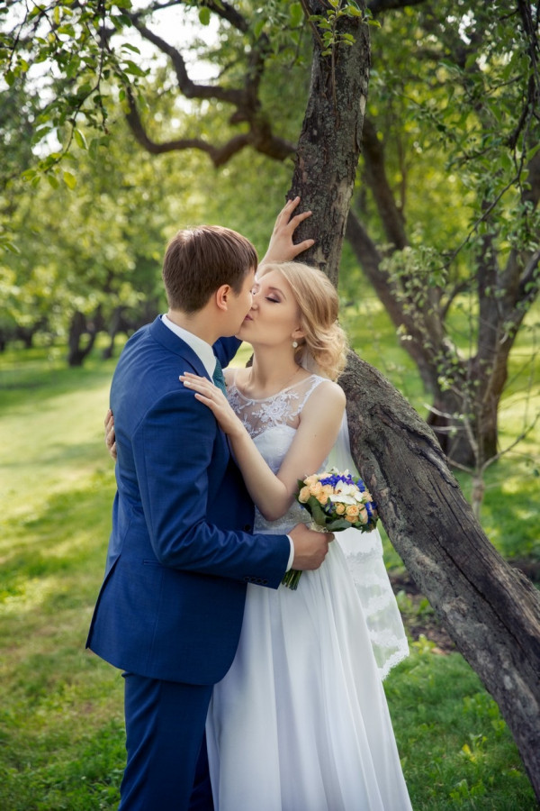 жених и невеста на свадебной прогулке возле дерева в парке Коломенское